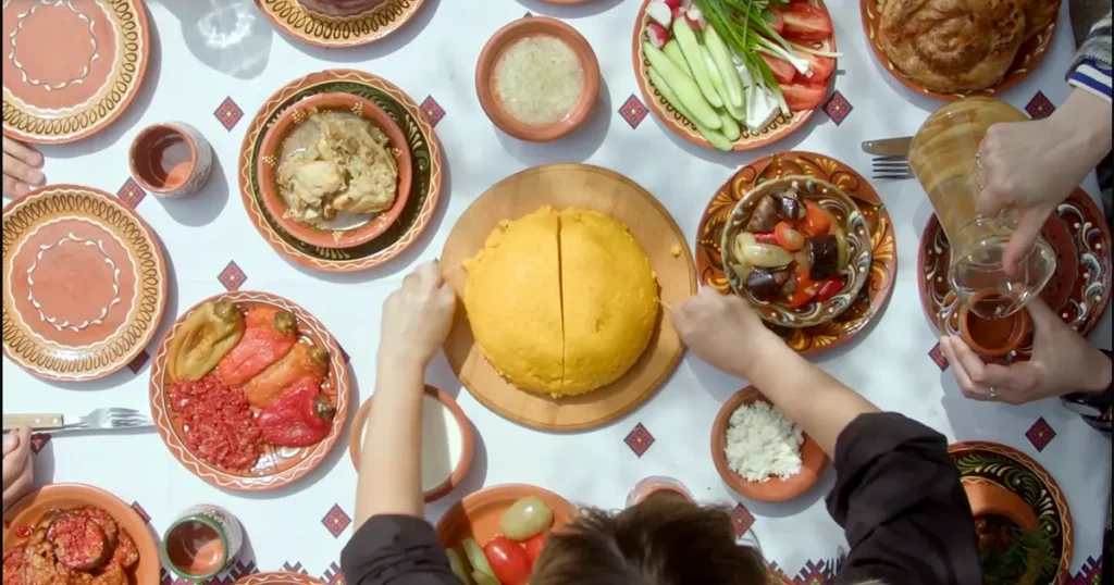 Traditional table in the Republic of Moldova with mămăligă cut with thread, cabbage rolls in clay pots, and rustic decor