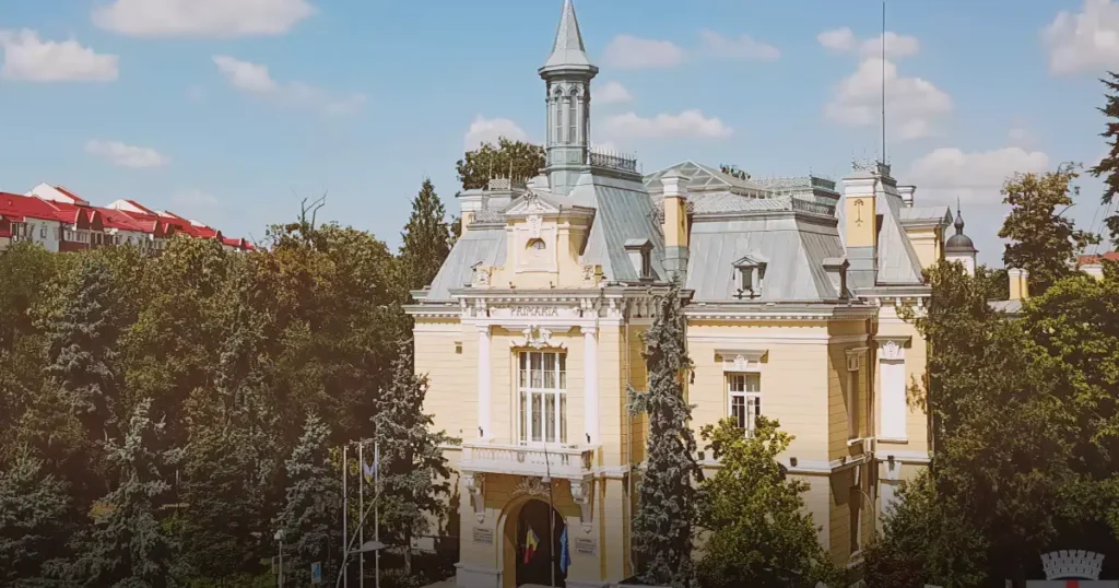 Architectural detail of the Botoșani City Hall facade, highlighting the eclectic style and heritage elements under a clear sky.
